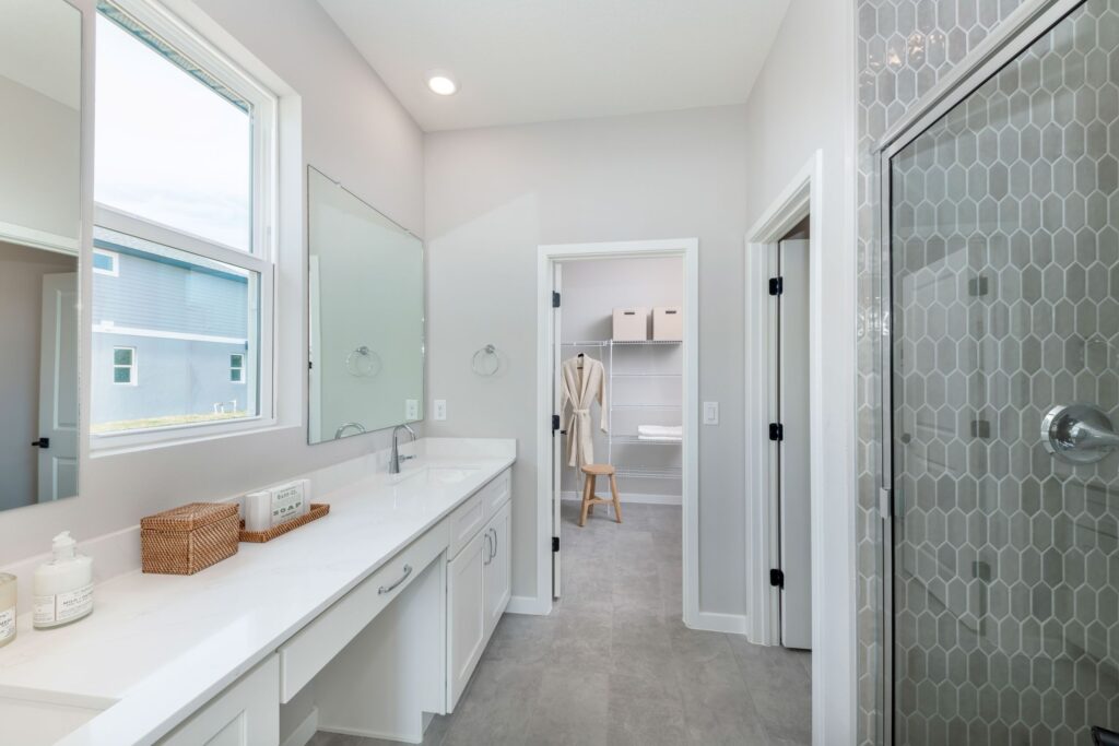 A bright, modern primary bathroom in the Bay model at Sabana Reserve featuring a spacious vanity, walk-in shower, and contemporary finishes.